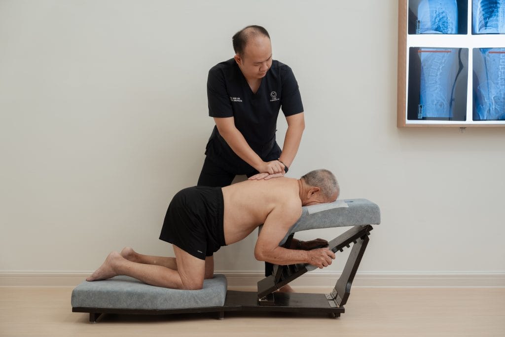 Rong Han doing single hand thoracic adjustment on knee chest table