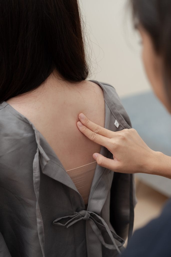 Pei Yun is doing a static palpation on a patient during chiropractic consultation
